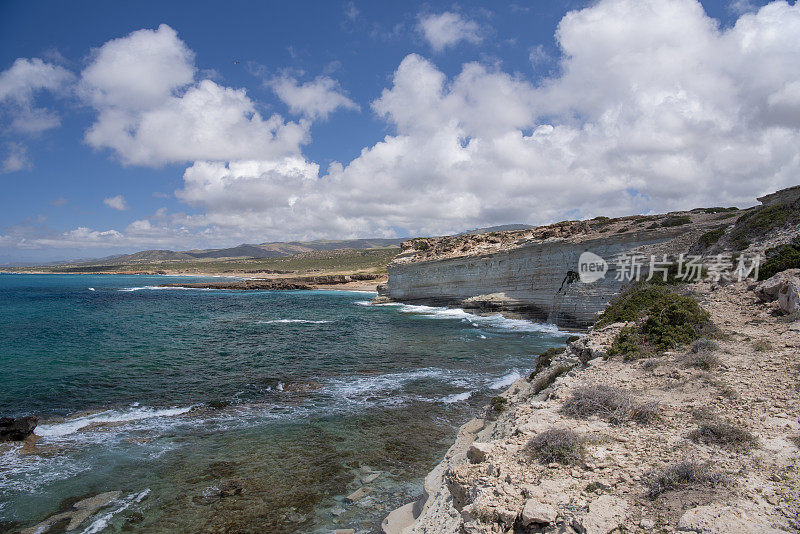 高海拔的崎岖，干旱的石灰岩斜坡和悬崖沿海岸线与清澈的海水色调和破碎的波浪