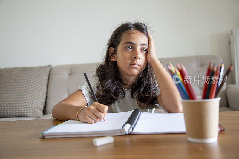 一个小女孩在家里的书桌上做作业