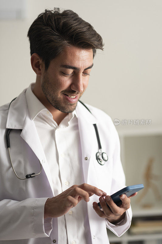 年轻英俊的男医生使用现代手机