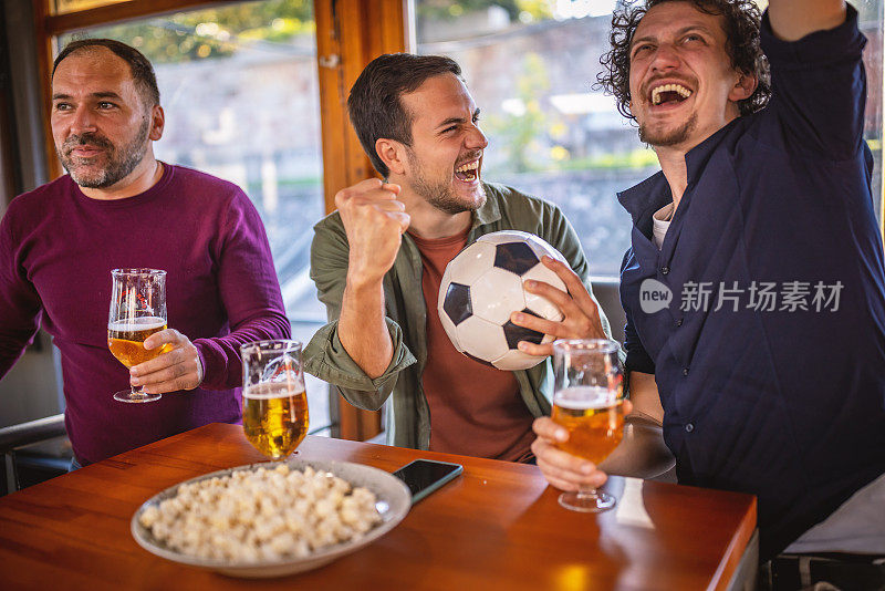兴奋的体育迷们一边在酒吧里观看比赛，一边为自己的球队加油