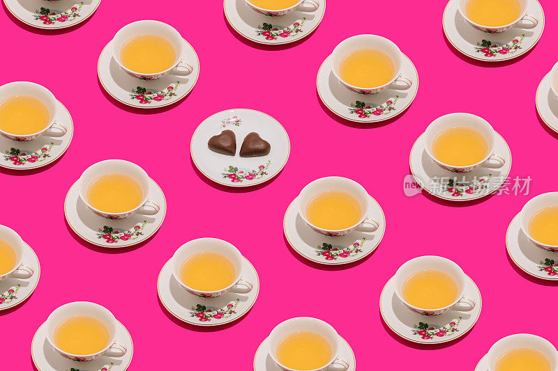 复古的浪漫成分的复古杯茶和两个巧克力心形在生动的粉红色背景。最小限度的爱或情人节模式。