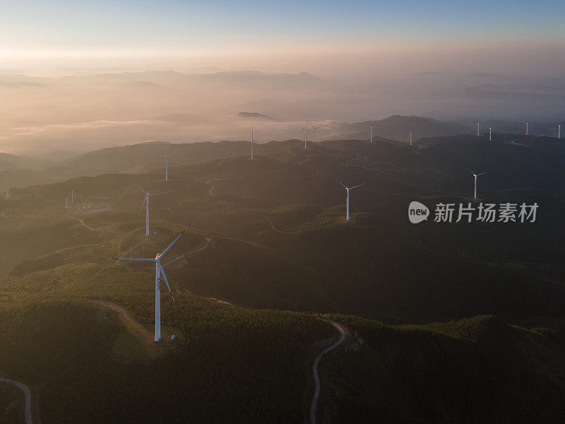 太阳照在山上的整排风力涡轮机上