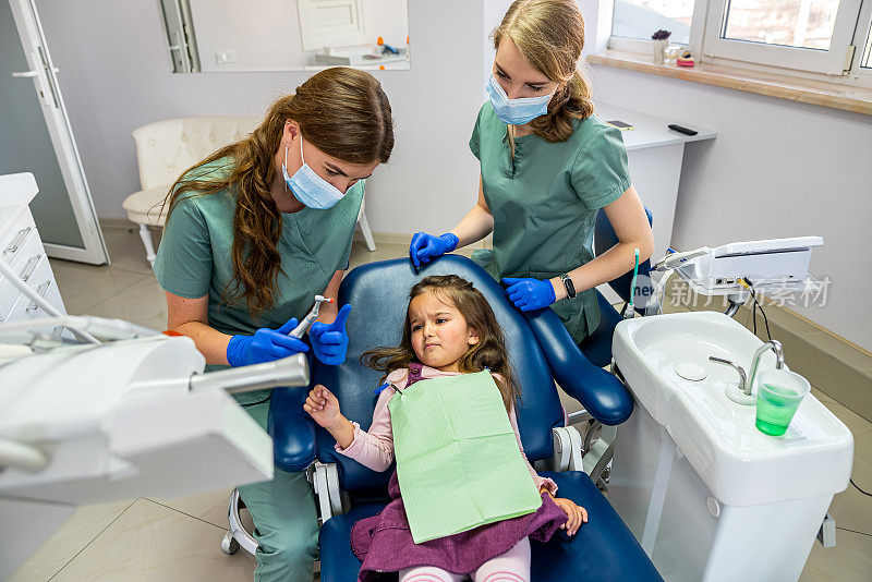 专业的女牙医正在给被带到接待处的小孩刷牙。