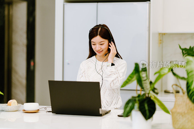 亚洲年轻女子对着摄像机视频通话，在家里与他的商业伙伴进行视频会议。