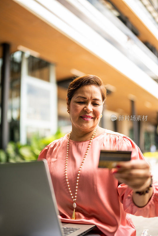成熟女人在户外用笔记本电脑网购