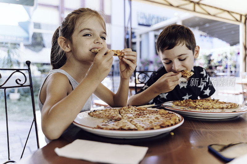 哥哥和妹妹在餐厅吃披萨。披萨。孩子的肖像