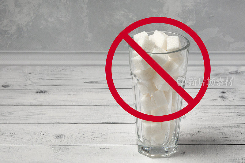 一个装满精制糖的玻璃杯，在它的前面有一个带斜线的红圈。放弃糖的概念，以及无添加糖的营养