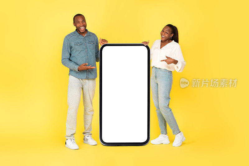 一对非洲夫妇指着黄色背景的大屏手机