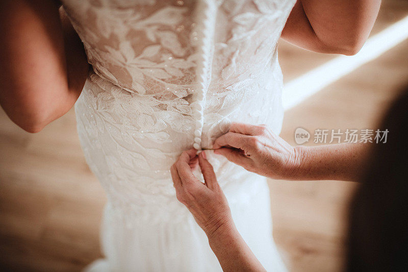 新娘的母亲正在给她的裙子拉上拉链