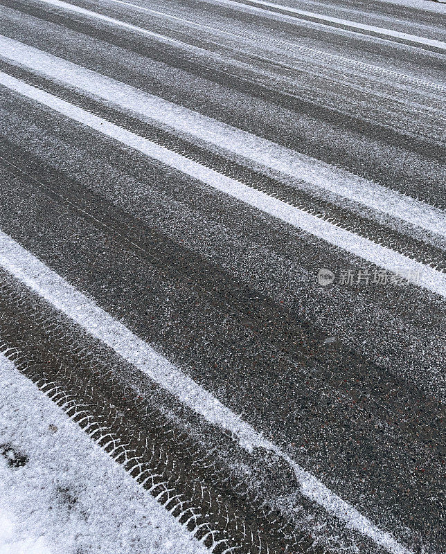 街道上新下的软雪上留下了汽车轮胎的印记。