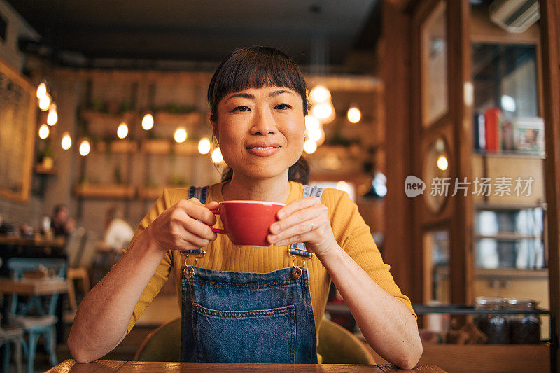 一位女士在咖啡馆里喝着卡布奇诺。