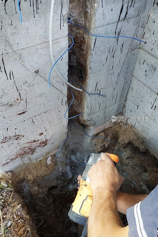 主人用打孔机拆卸电缆，在墙上撞出一个电缆壁龛。