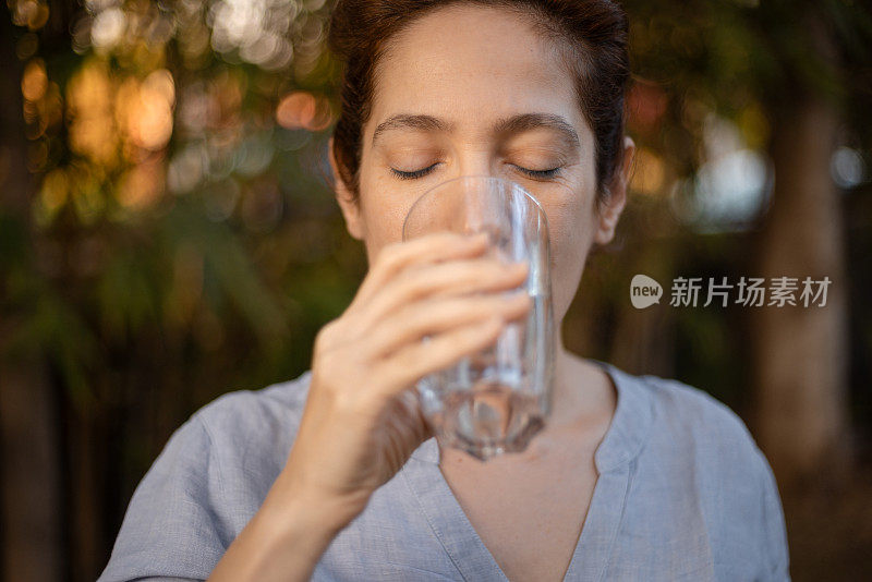 白种人妇女在除去冰块后啜一口冷水，如释重负，这是一系列治疗敏感牙齿的一部分