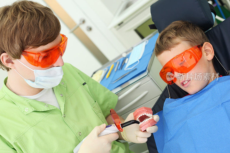 牙医和男孩一起看紫外线治疗仪