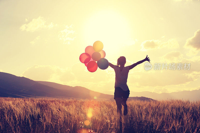 在草地上用彩色气球为年轻的亚洲妇女欢呼