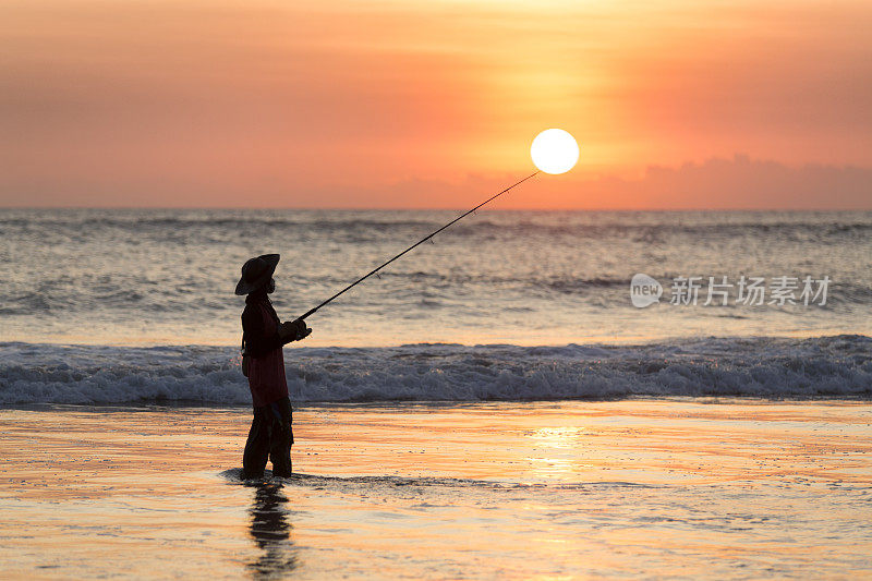 印度尼西亚巴厘岛海滩上的渔民和红色日落