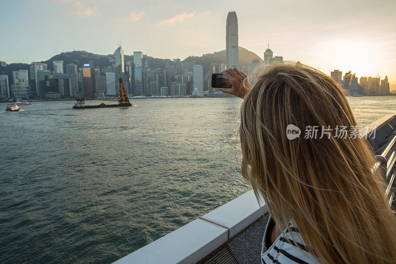 一名女子用手机拍下香港的天际线