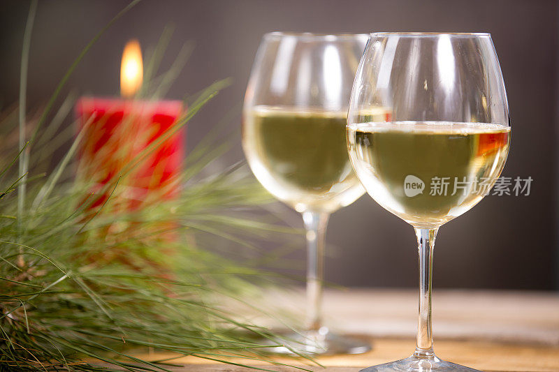 两杯白葡萄酒，杯子和红蜡烛。松树。圣诞节。