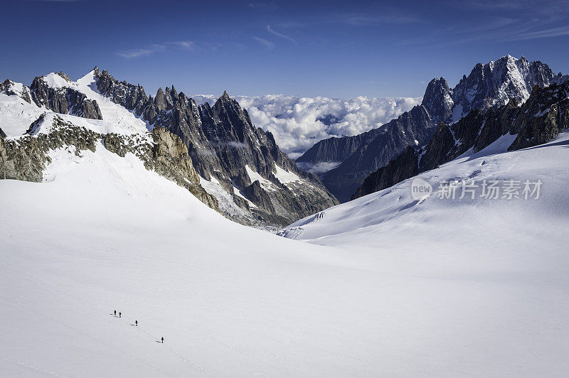 登山运动员在阿尔卑斯山脉参差不齐的山峰之间翻越雪原