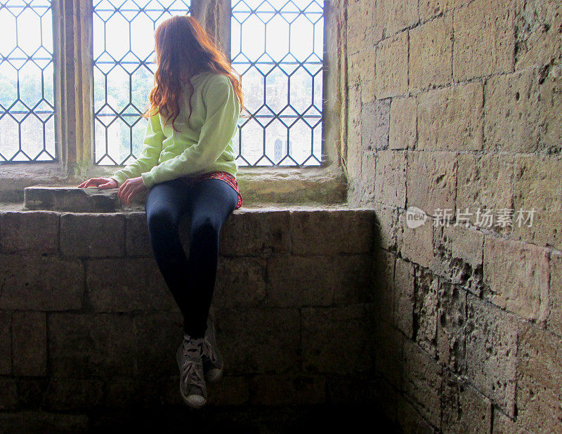 女孩坐在靠墙的窗台上，望着外面的铅窗