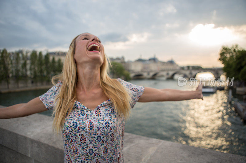 俯瞰巴黎塞纳河的桥上，快乐的女人张开双臂――自由