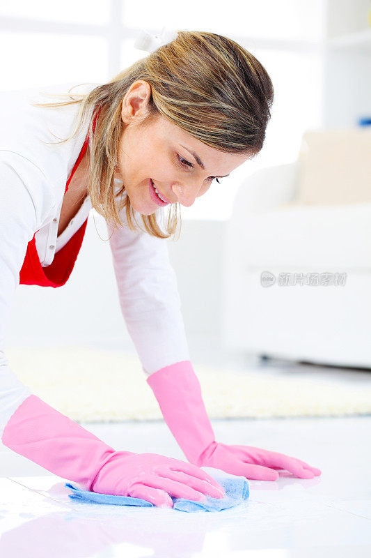 戴着手套在打扫地板的快乐年轻女人