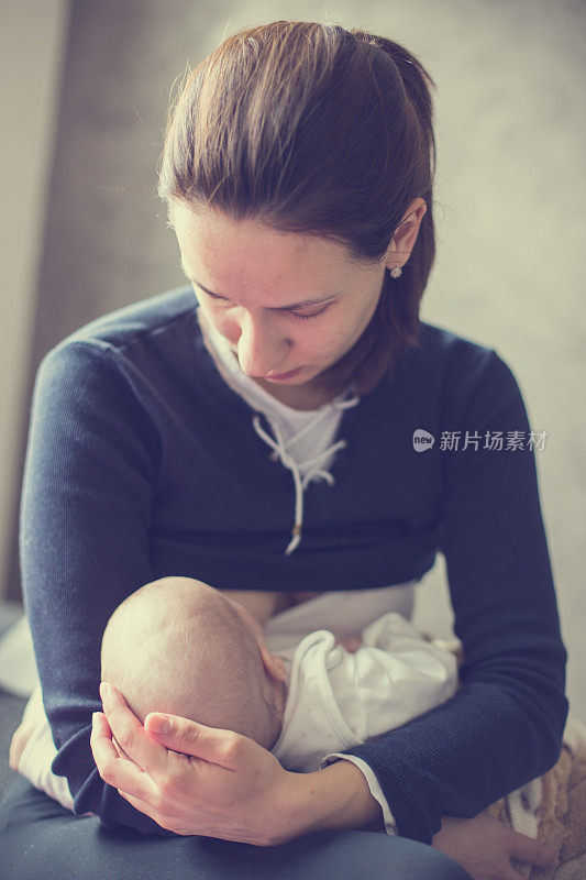 年轻的母亲正在母乳喂养她的新生儿