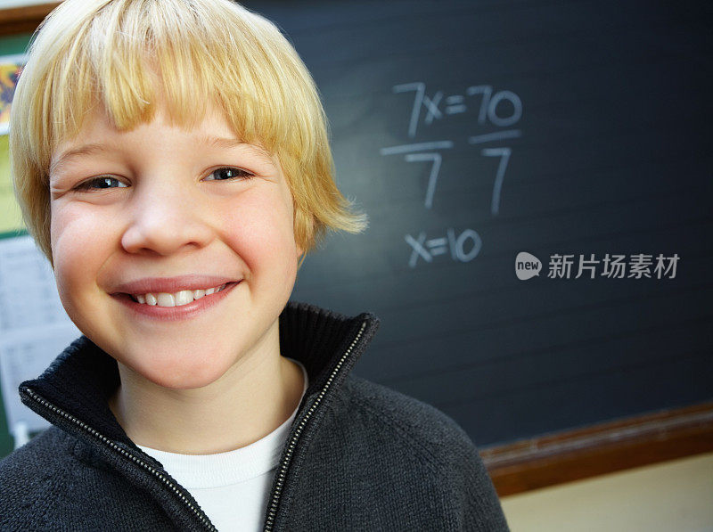 快乐可爱的男孩在教室里靠在黑板上