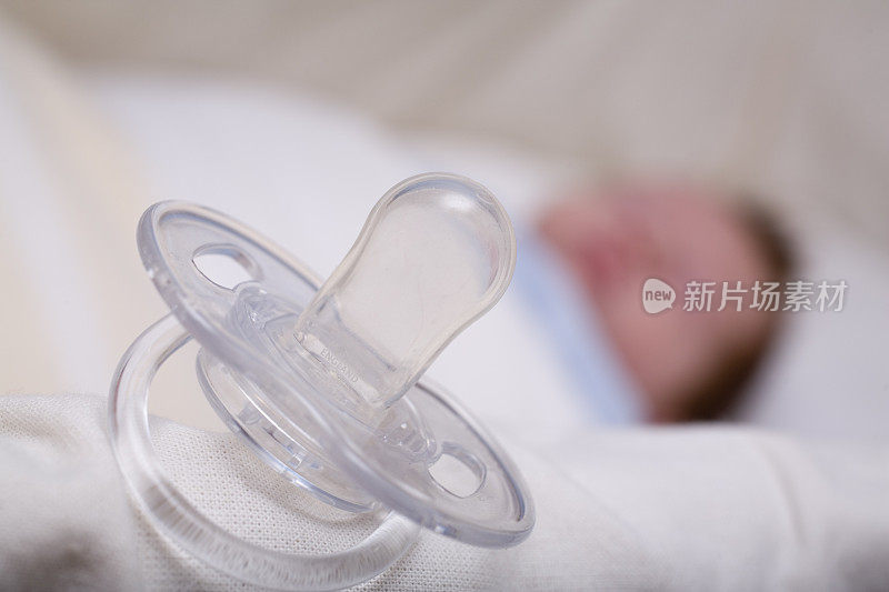 透明的奶嘴放在熟睡的新生儿的婴儿床上