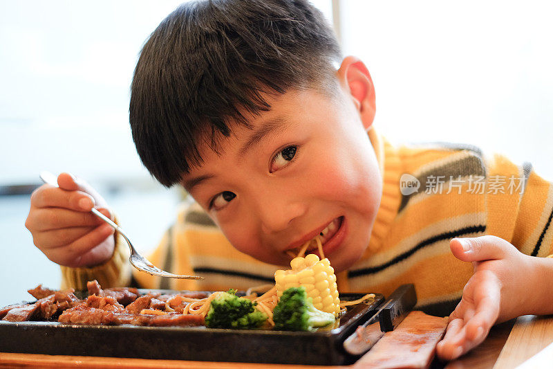 亚洲男孩在餐厅吃牛排