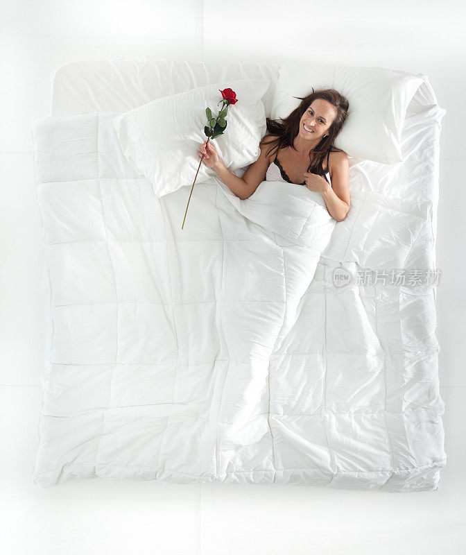 女人拿着玫瑰花躺在床上