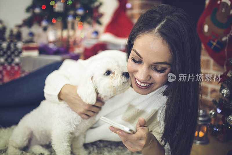 一个女人和她的狗在圣诞树前。