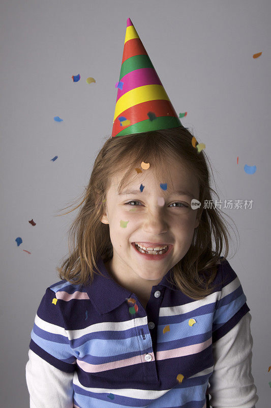 带着派对帽和五彩纸屑的微笑女孩