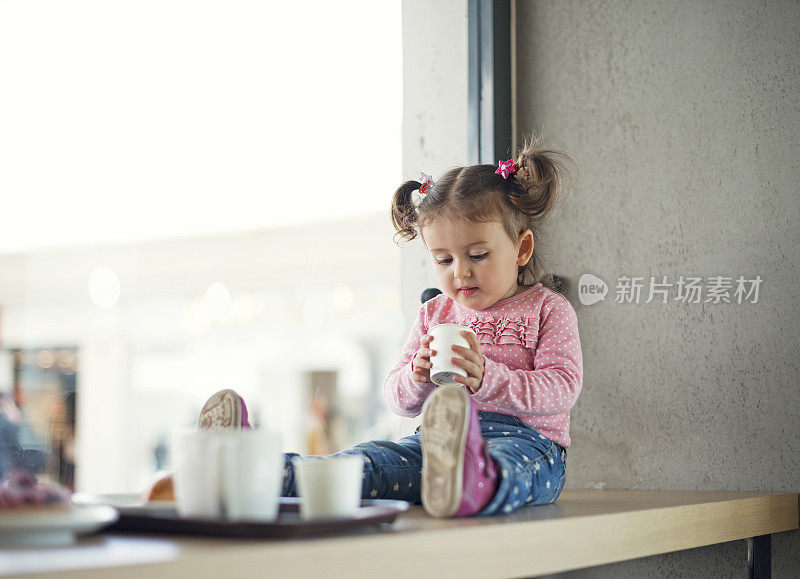 蹒跚学步的小女孩在咖啡厅喝热巧克力