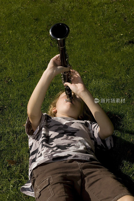 男孩躺在草地上吹单簧管