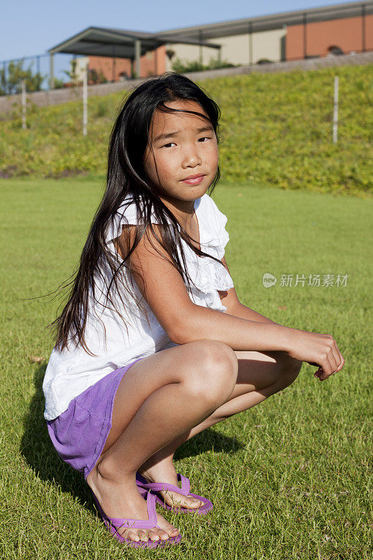 年轻的亚洲女孩跪在公园里