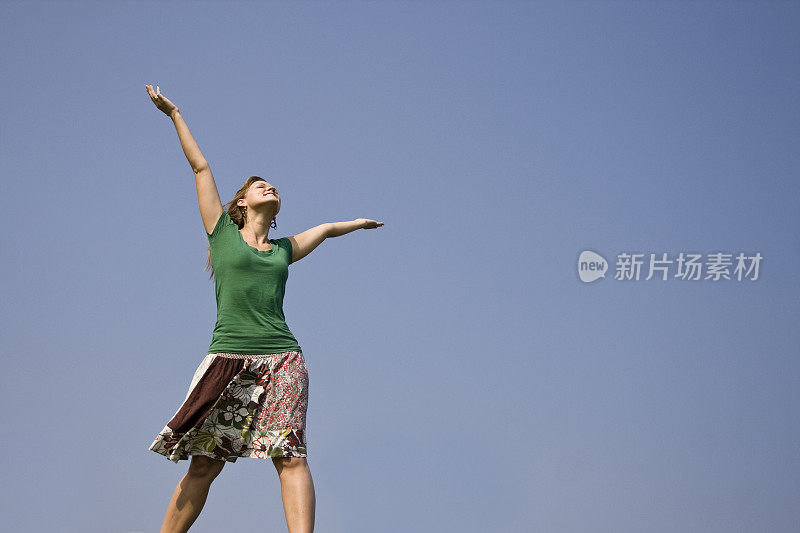 年轻女子举起双手望向天空。