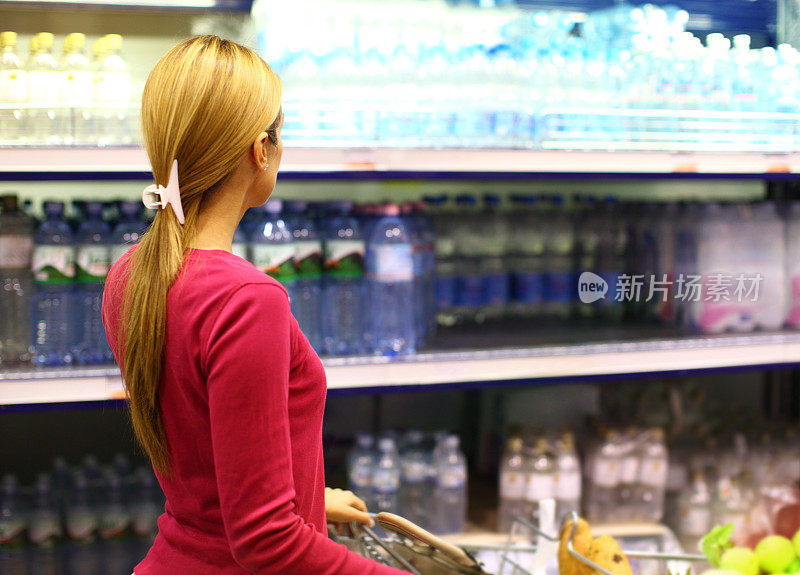 在超市选购水的女人。