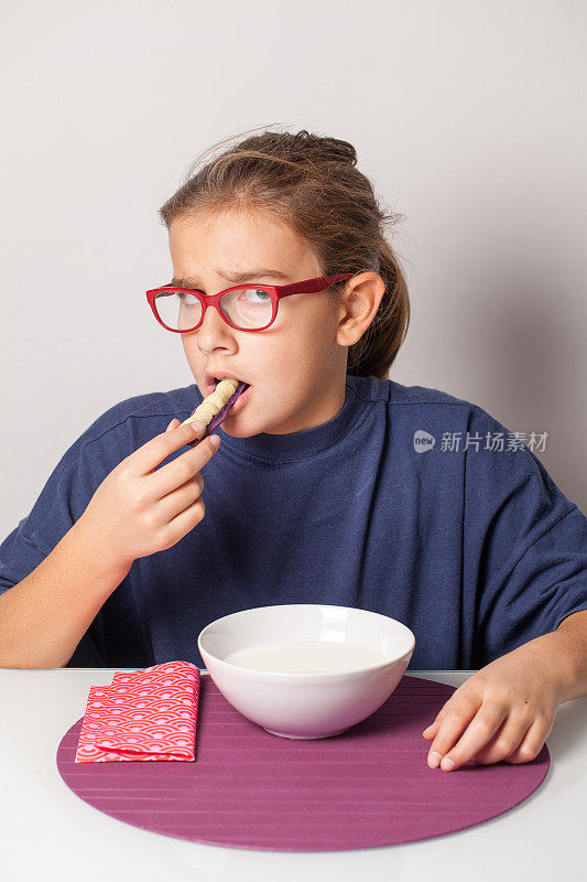 小女孩怀疑地咬着万圣节的骷髅手指饼干