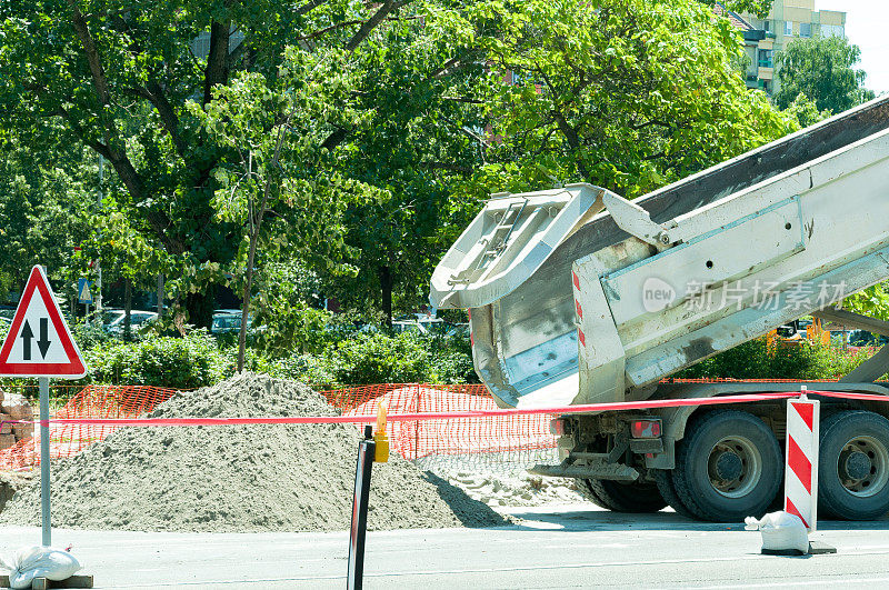 自卸卡车在街道工地上卸沙子。卡车的尾部。