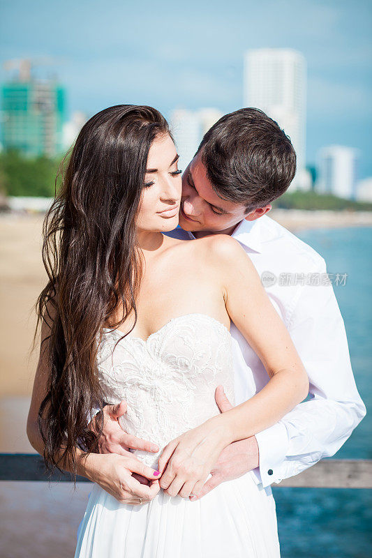 新婚夫妇在豪华度假村举行婚礼后互吻。浪漫的新娘和新郎在游泳池附近放松。蜜月。