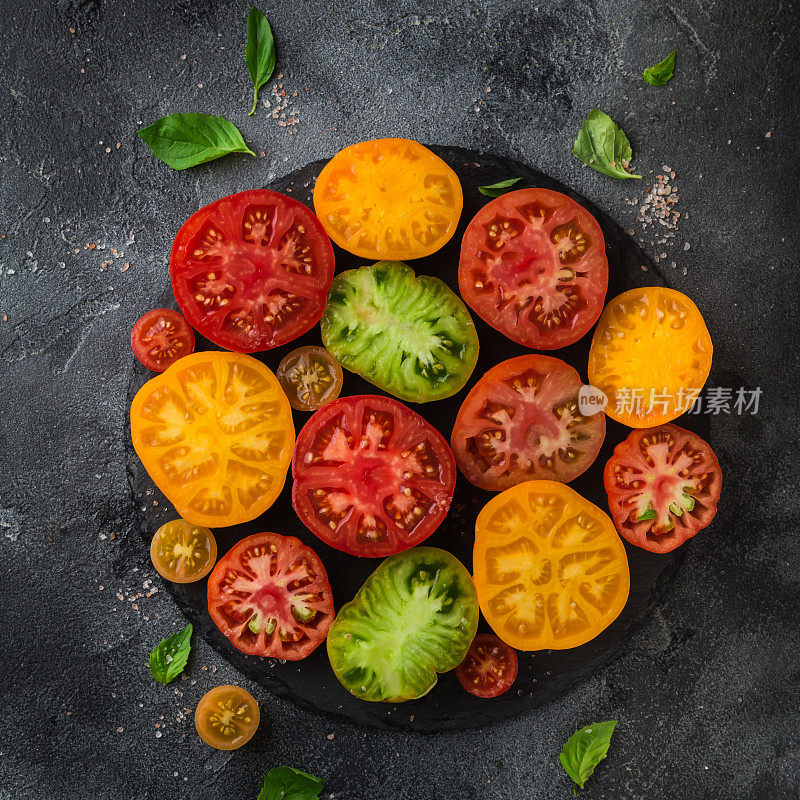 新鲜的有机彩色西红柿，黑色的盘子，黑色的背景