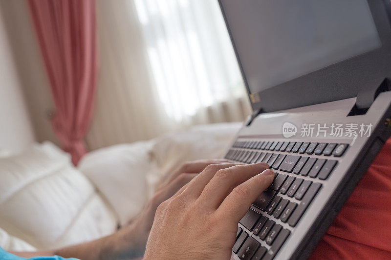 男人的手在家里的笔记本电脑键盘上打字。在网上浏览信息的人。自由博客，它支持概念