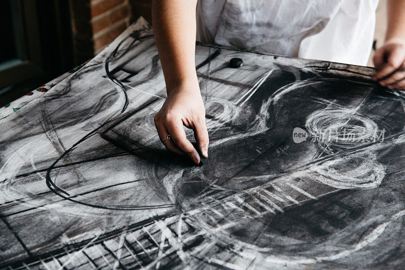年轻的女画家用木炭在纸上作画