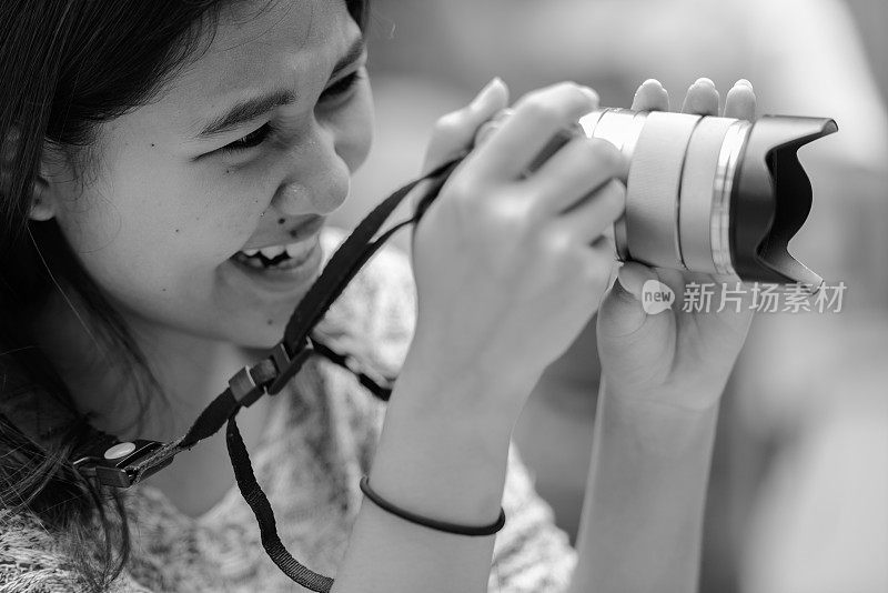 一名年轻的亚洲少女在餐厅休息时用相机拍摄的黑白照片