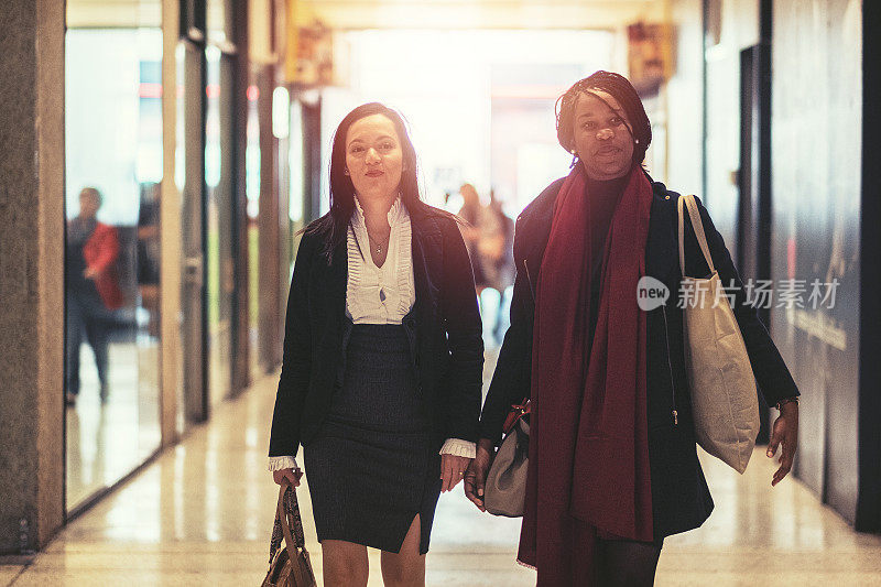 两个中年女商人走在城市里