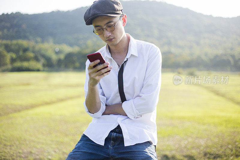 年轻人戴着便帽坐在凳子上打电话