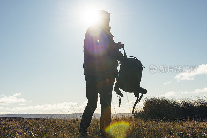 男人在秋日的阳光下徒步旅行。