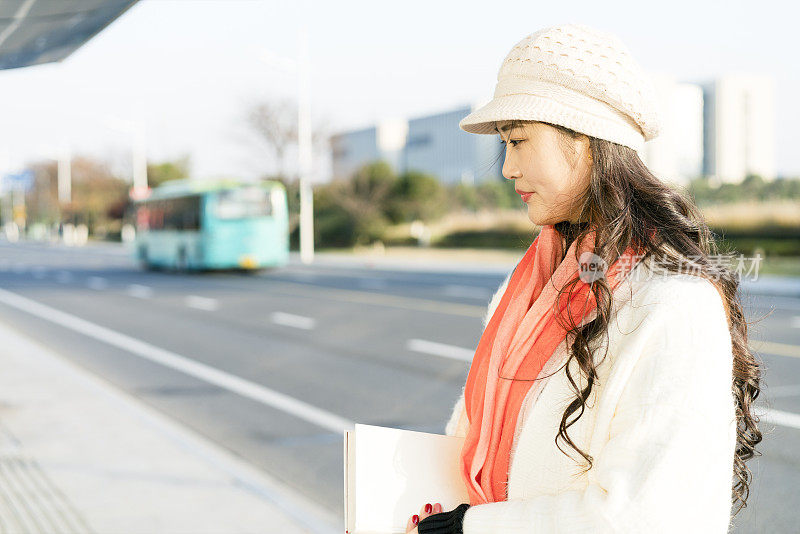 冬天的女人拿着一本书在城市里