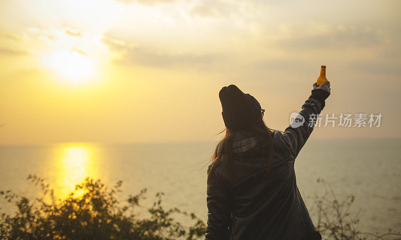 夕阳西下，年轻女子喝着啤酒